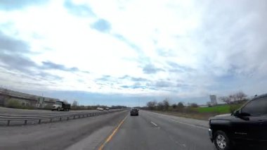 Gündüz vakti otoban boyunca araba sürmek. Beyaz bulutlar parlak bir mavi gökyüzünde sürükleniyor. POV görünümü. Zaman ayarlı. ABD KY Louisville 28 Mart 2025. Yüksek kalite 4k görüntü