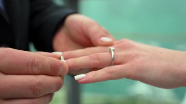 Bir damadın tören sırasında gelin parmağına alyans takıp sembolik bir aşk, söz ve bağlılık anı yakaladığı yakın plan. Yüksek kalite 4k görüntü