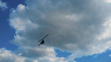 Helikopter gökyüzünde uçuyor, büyük bulutların arasından geçerken hafifçe hareket ediyor. Gökyüzüne karşı hareket eden bir uçağın dramatik görüntüsü. Waukegan IL 6 Eylül 2025. Yüksek kalite 4k görüntü