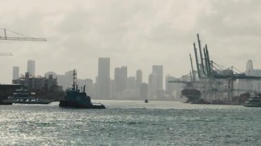 Kargo iskelesi, su üzerinde vinçler ve gemiler, endüstriyel liman silueti sislerin arasından görülebiliyor, karamsar bir deniz manzarası yaratıyor. Yüksek kalite 4k görüntü