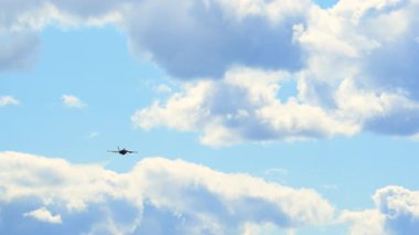 Askeri savaş uçağı mavi gökyüzüne doğru sürüklenen bulutlarla uçuyor ve hava üssü altyapısıyla dinamik bir havacılık sahnesi yaratıyor. Alt manzara. Yüksek kalite 4k görüntü