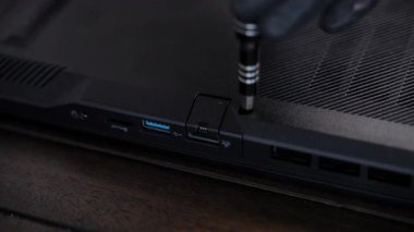 Bilgisayarın arka kapağını açmak ve elektronik cihazı tamir etmek için tornavida kullanan bir teknisyenin yakın çekimi. Sahne, hassas donanım bakımını gösteriyor. Yüksek kalite 4k görüntü