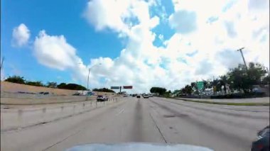 POV Timelapse güneşli otoyolda trafik ve bulutlu gökyüzü ile birlikte şehir merkezine doğru gidiyor. Parlak, dinamik bir şehir seyahati sahnesi yaratıyor. Zaman aşımı USA IL Miami 01 Nisan 2025. Yüksek kalite 4k görüntü