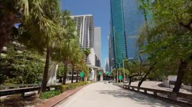POV 'un hızlandırılmış sürüşü altında yüksek binalar ve palmiye ağaçları bulunan modern bir kıyı şehrinde hızla hareket eden şehir hareketlerini ve tropikal manzaraları gösteriyor. USA IL Miami 01 Nisan 2025. Yüksek kalite 4k görüntü