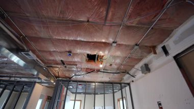 Tamamlanmamış iç tavan, açıkta duran havalandırma kanalları, yalıtım ve metal duvar çerçevesi. İnşaat sırasında mekanik sistem kurulumu. Yüksek kalite 4k görüntü