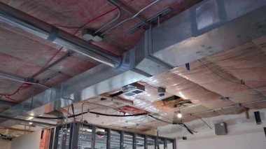 HVAC kanalları, yalıtımı ve metal duvar çerçevesi ile tamamlanmamış iç tavan görüntüsü. İnşaat sırasında mekanik sistem kurulumu. Yüksek kalite 4k görüntü
