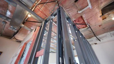 HVAC kanalları, yalıtımı ve metal duvar çerçevesi ile tamamlanmamış iç tavan görüntüsünün POV 'u. İnşaat sırasında mekanik sistem kurulumu. Yüksek kalite 4k görüntü