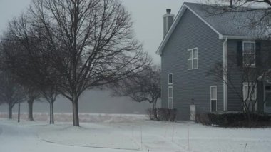 Banliyö sokağına sert kar yağar, evleri ve çıplak kış ağaçları vardır. Soğuk hava, kış atmosferi ve sakin yaşam. Yüksek kalite 4k görüntü