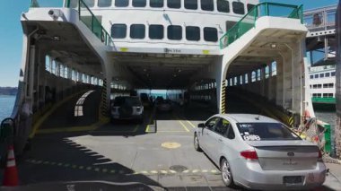Limanın altyapısı, güvenlik personeli ve yüksek geçitler görülebildiği için arabalar feribot terminali yükleme alanından geçiyor. ABD Seattle, WA 25 Temmuz 2025. Yüksek kalite 4k görüntü