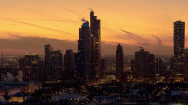 Gün batımında Chicago 'nun merkezindeki gökdelenler sıcak akşam ışıklarıyla aydınlanıyor. Şehir ışıkları yanmaya başlarken şehir binaları dramatik bir gökyüzüne karşı parlıyor. Yüksek kalite 4k görüntü