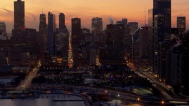 Chicago şehir merkezinin parlayan gökdelenleri ve aydınlatılmış liman manzarası. Karla kaplı kıyı şeridi ve şehir ışıkları çarpıcı bir kış kentsel atmosferi yaratır. Yüksek kalite 4k görüntü