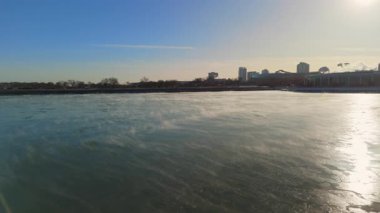 Buzlu göl yüzeyine, kış mevsimi dokusuna, soğuk hava manzarasına ve doğal arka plana yansıyan altın güneş ışığının tepeden tırnağa görüntüsü. Yüksek kalite 4k görüntü