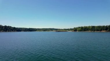 Seyahat ve seyahat kavramı. Berrak yaz gökyüzü altında sakin mavi göl ve uzak orman kıyı şeridi, huzurlu doğa manzarası ve seyahat yeri konsepti. Yüksek kalite 4k görüntü
