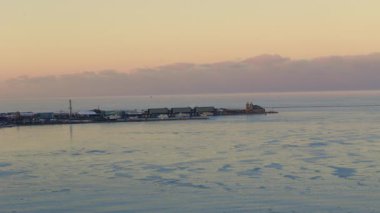 Kış gölü limanı buz oluşumları ve gün batımında uzak rıhtım soğuk mevsimsel manzara ve sakin sahil manzarası. Yüksek kalite 4k görüntü