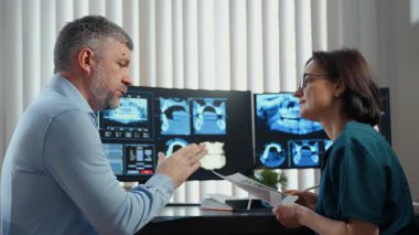 Diş hekimi danışmanı, diş röntgenleri ve röntgenleri, modern diş kliniği teşhisleri ve ağız sağlığı hizmetleri incelenirken. Yüksek kalite 4k görüntü