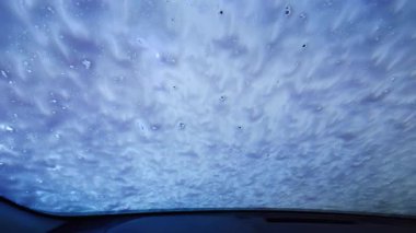 Otomatik yıkama sisteminden geçen bir arabanın içinde. Su spreyi ve dönen fırçalar temizlik aracı. Geniş çaplı görüntüler. Yüksek kalite 4k görüntü