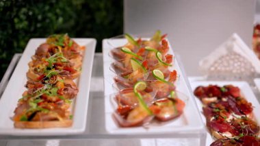 Cam tezgahlarda düzgünce sergilenen gurme aperatifleri olan masanın kamera görüntüsünü hareket ettir. Renkli abur cuburlar yemek ya da kutlama için iyi düzenlenir. Yüksek kalite 4k görüntü