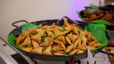 Açık büfe masasına yakın çekim. Kapalı bir etkinlikte ya da partide ısıtma tepsilerinde servis edilen kızarmış aperatifler ve patates dilimleri. Misafirler için sıcak yemek hazırlığı. Yüksek kalite 4k görüntü