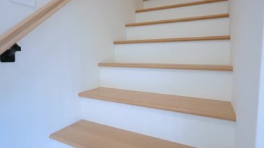 İç merdiven, ahşap basamaklar ve parlak bir konutun içindeki korkuluklar. Beyaz duvarları ve doğal ahşabı olan temiz bir mimari tasarım. Yüksek kalite 4k görüntü