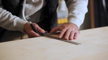 Carpenter measuring and marking wooden board with ruler and pencil during woodworking preparation in workshop. High quality 4k footage