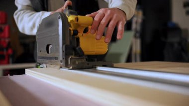 Marangoz inşaat ya da yenileme çalışmaları sırasında elektrikli testere kullanarak odun kesiyor. Bir atölyede çalışan elektrikli aletin görüntüsünü kapat. Yüksek kalite 4k görüntü