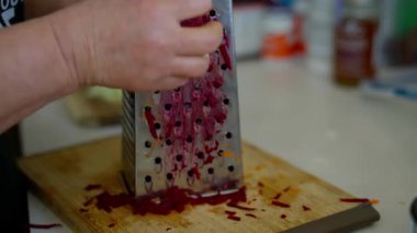 Tahta kesme tahtasının üzerinde metal rendesi olan elleri ızgara pancar. Yüksek kalite 4k görüntü