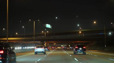 Gece bir otoyolda kavşakların altında parlayan farları ve stop lambaları olan birden fazla araba var. Şehir ulaşımı, gece trafiği. ABD Şikago, 2 Ocak 2026. Yüksek kalite 4k görüntü