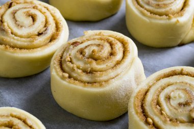 Cinnabon. Ev yapımı tarçınlı rulo. Pişirme tepsisinde çiğ rulo