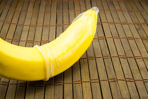 Banana com preservativo sobre fundo de madeira — Fotografia de Stock