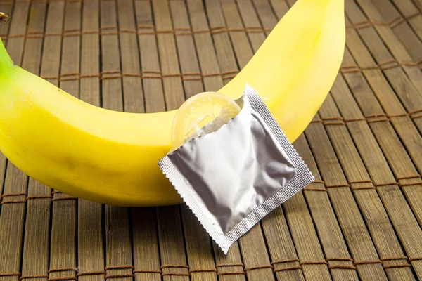 Banana com preservativo sobre fundo de madeira — Fotografia de Stock