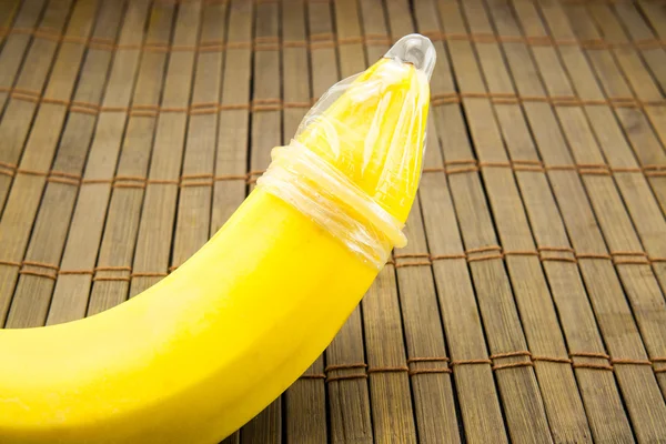 Banana com preservativo sobre fundo de madeira — Fotografia de Stock