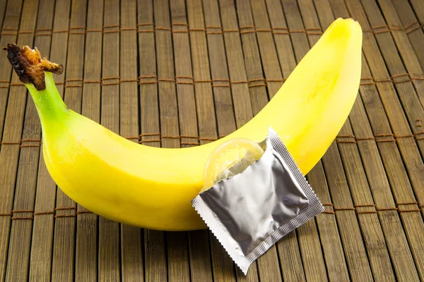 Banana com preservativo sobre fundo de madeira — Fotografia de Stock