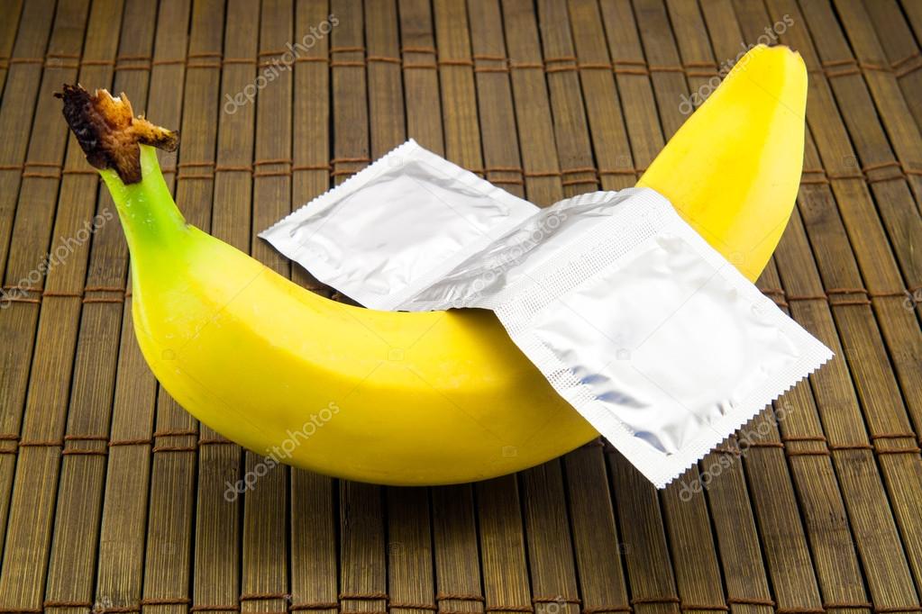 Banana with condom on wooden background