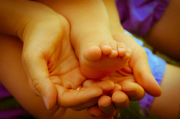 Piedi del bambino nelle mani femminili — Foto Stock