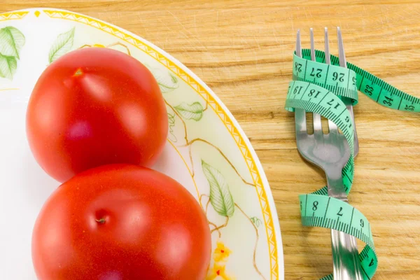 Measuring tape and a fork with tomato isolated