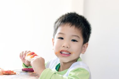 Küçük Asyalı çocuk yakından beyaz arka plan üzerinde pizza yiyor