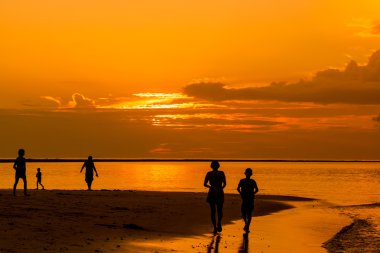 Gün batımında iyon plaja yürüme Kişilik grubun siluetleri