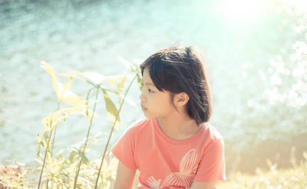 Sad little girl in natural bokeh background — Stock Photo, Image