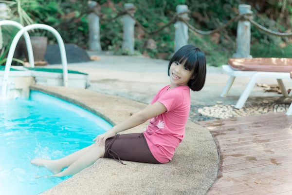 Kobieta basen relaksujący siedzący w letnią sukienkę z nogami w basenie — Zdjęcie stockowe