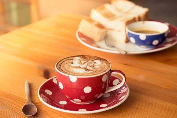 Uma xícara de café em uma xícara vermelha no fundo de madeira — Fotografia de Stock