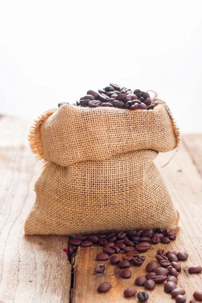 Coffee beans in bag on wood — Stock Photo, Image