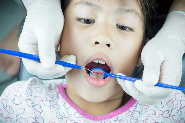 Nahaufnahme eines kleinen Mädchens mit einem Zahnarzt, der die Zähne einer Patientin untersucht — Stockfoto