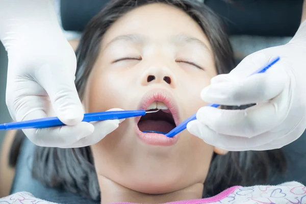 Nahaufnahme eines kleinen Mädchens mit einem Zahnarzt, der die Zähne einer Patientin untersucht — Stockfoto