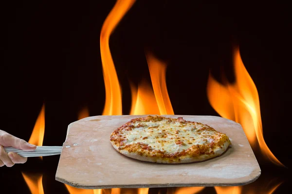 Mano spingendo la pizza finita dal forno con la pizza sho — Foto Stock