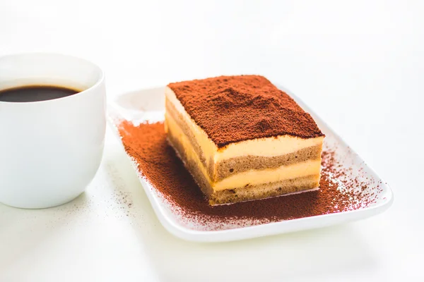 Gustosa torta tiramisù con tazza di caffè su sfondo bianco — Foto Stock