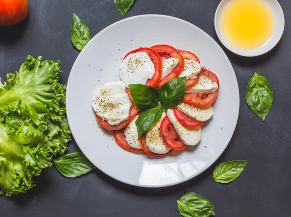 Caprese salad with mozzarella, tomato, basil on white plate. Top — Stock Photo, Image