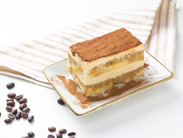 Tasty tiramisu cake with coffee beans on white — Stock Photo, Image