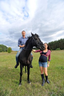 Çocuğu bekliyor, çayırda yürüyor. Ekose fanila gömlekli genç bir çift - uzun saçlı, uzun boylu, yakışıklı bir esmer, adam uzun boylu ve cesur, siyah bir ata biniyor..
