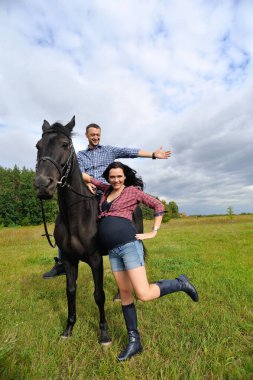 Çocuğu bekliyor, çayırda yürüyor. Ekose fanila gömlekli genç bir çift - uzun saçlı, uzun boylu, yakışıklı bir esmer, adam uzun boylu ve cesur, siyah bir ata biniyor..