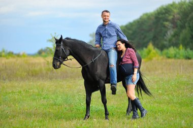 Çocuğu bekliyor, çayırda yürüyor. Genç bir çift - o uzun saçlı yakışıklı bir esmer, hamile; o uzun boylu ve cesur, siyah bir ata biniyor.